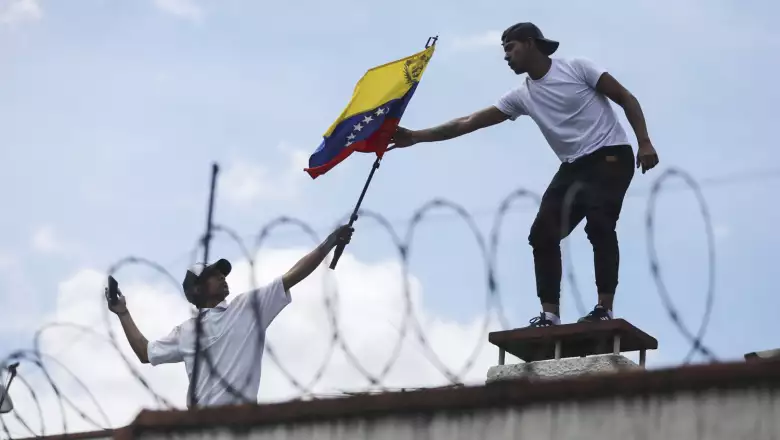 A man gives a flag of Venezuela to one another, on the roof of the Consulate of Venezuela, during a protest in Bogota