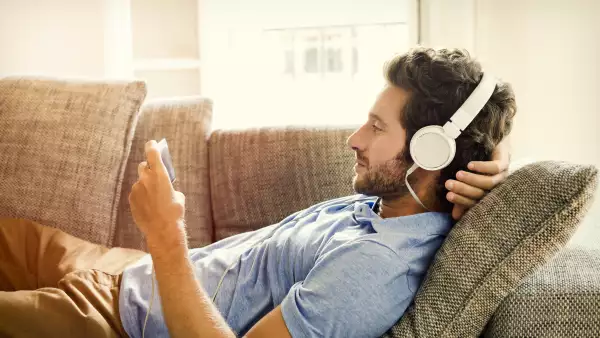 Hombre en el sofá ve una película en el teléfono móvil