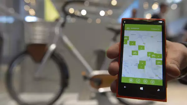 Un empleado posa con un teléfono inteligente para demostrar un sistema de intercambio de bicicletas llamado Contoso Bikes.