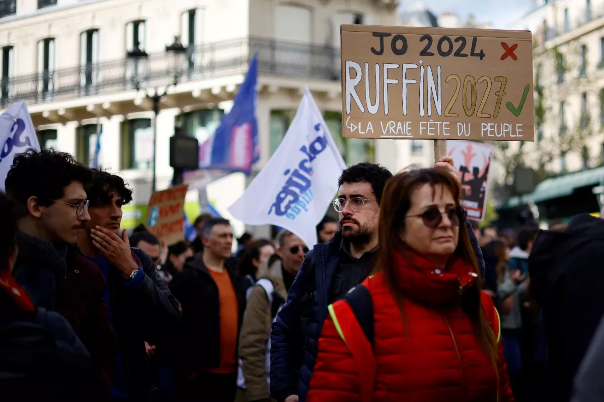 Los manifestantes sostienen carteles durante una manifestación como parte del duodécimo día de huelgas y protestas a nivel nacional contra la reforma de las pensiones del gobierno francés, en París, Francia, el 13 de abril de 2023. El lema dice "Juegos Olímpicos 2024, Ruffin 2027, el día de la gente real".