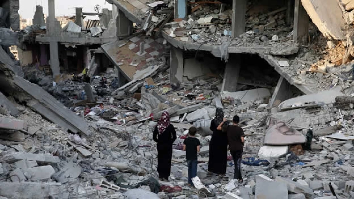 Un grupo de palestinos caminan entre los escombros de casas destruidas en Gaza este domingo