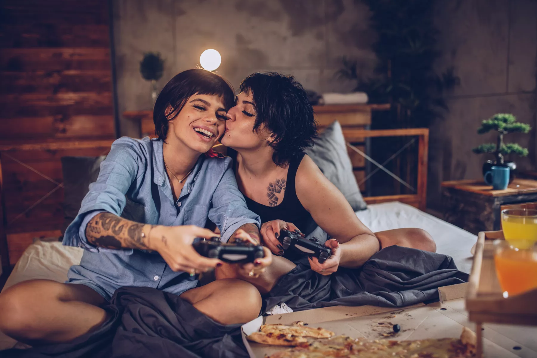 Dos mujeres jugando videojuegos y besándose