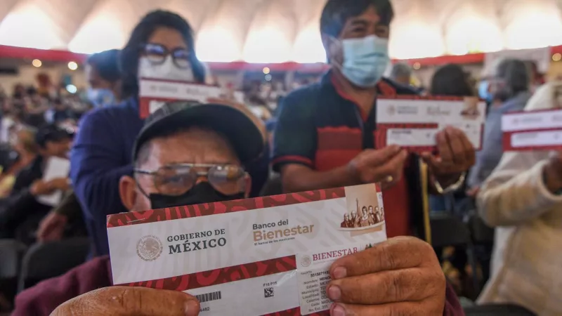 Hombre en primer plano mostrando el cambio de su tarjeta para recibir la pensión Bienestar de adultos mayores. 