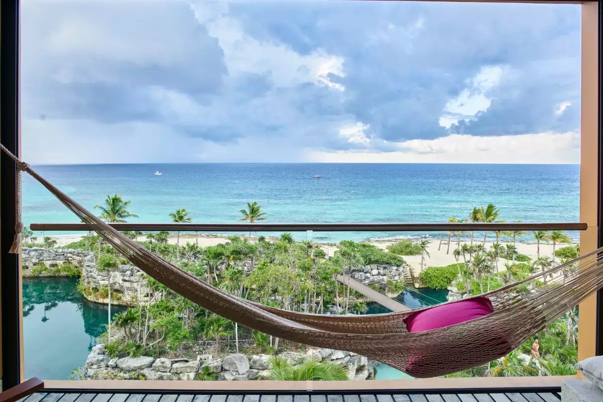Vista de una habitación Suite Ocean Front Doble a la playa con amaca y cojín rosa para disfrutar