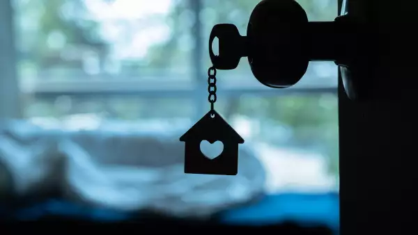House key with home keyring in keyhole on wood door, copy space
