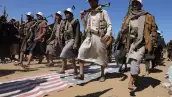 Los miembros de las tribus leales a los hutíes marchan contra las banderas estadounidenses e israelíes durante un desfile militar para nuevos reclutas tribales en medio de la escalada de tensiones con la coalición liderada por Estados Unidos en el Mar Rojo, en Bani Hushaish, Yemen, el 22 de enero de 2024.