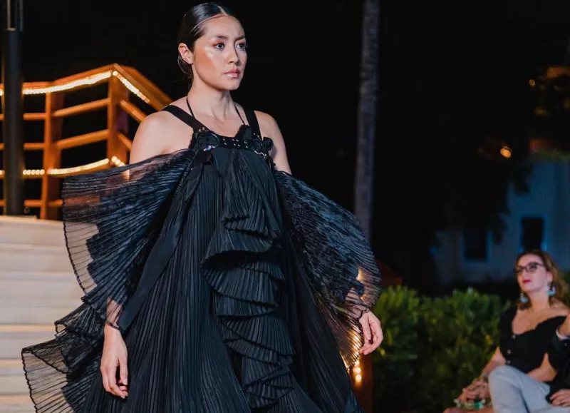 Mujer modelando con un vestido negro de Guillermo Jester. 