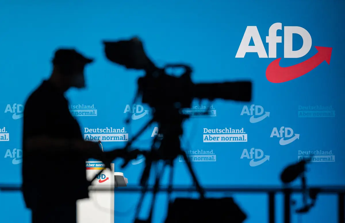 Un camarógrafo hace una silueta contra una pared con el logotipo de la AfD durante un congreso del partido ultraderechista alemán Alternativa para Alemania (AfD - Alternative fuer Deutschland) en Dresde, este de Alemania, el 11 de abril de 2021. 