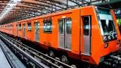 Tren naranja del Metro de la Ciudad de México detenido en una estación, visto de costado y con la cabina al frente.