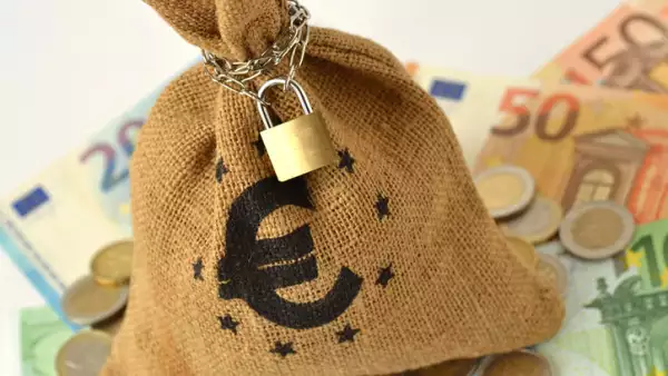 Money bag with padlock and chain over euro banknotes and coins - Saving money and financial security concept
