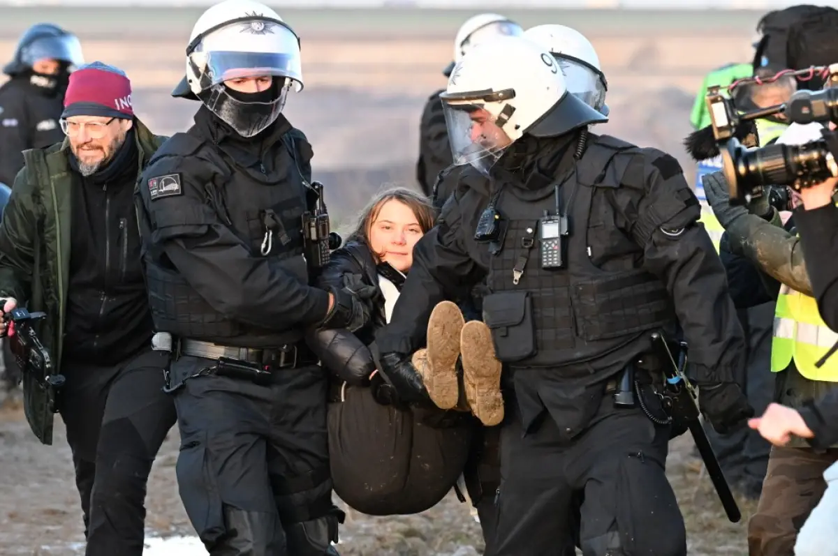 Dos agentes de la policía cargan a la activista climática sueca Greta Thunberg. 
