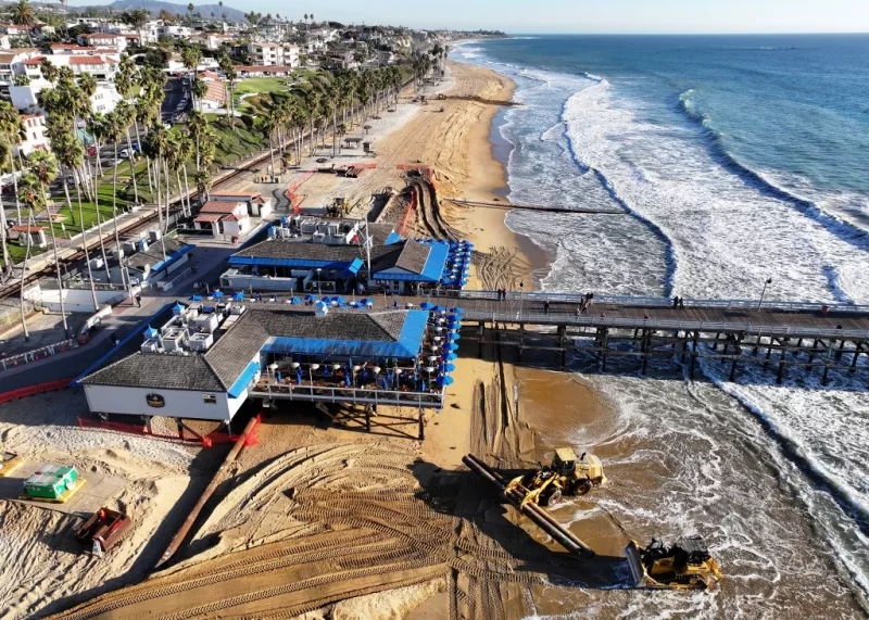 En una vista aérea, el trabajo continúa en un proyecto de reposición de arena a lo largo de la costa erosionada el 21 de noviembre de 2024 en San Clemente, California. El proyecto está agregando 251.000 yardas cúbicas de arena a la playa principal de San Clemente para reducir la erosión costera, los daños por tormentas y las fallas de los acantilados costeros, al tiempo que mejora el acceso a la playa a lo largo de un corredor vital de Amtrak. El desarrollo urbano en la zona contribuye a la erosión al interrumpir la reposición de arena natural.