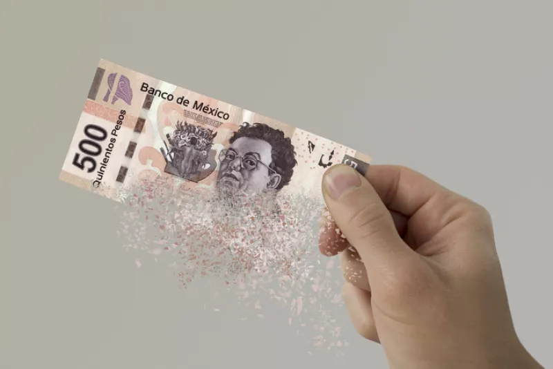 Mexican Pesos bill pulverizes in a man's hand.