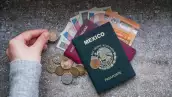 Contando dinero de diferentes países y un pasaporte mexicano y un pasaporte rumano en un lado.