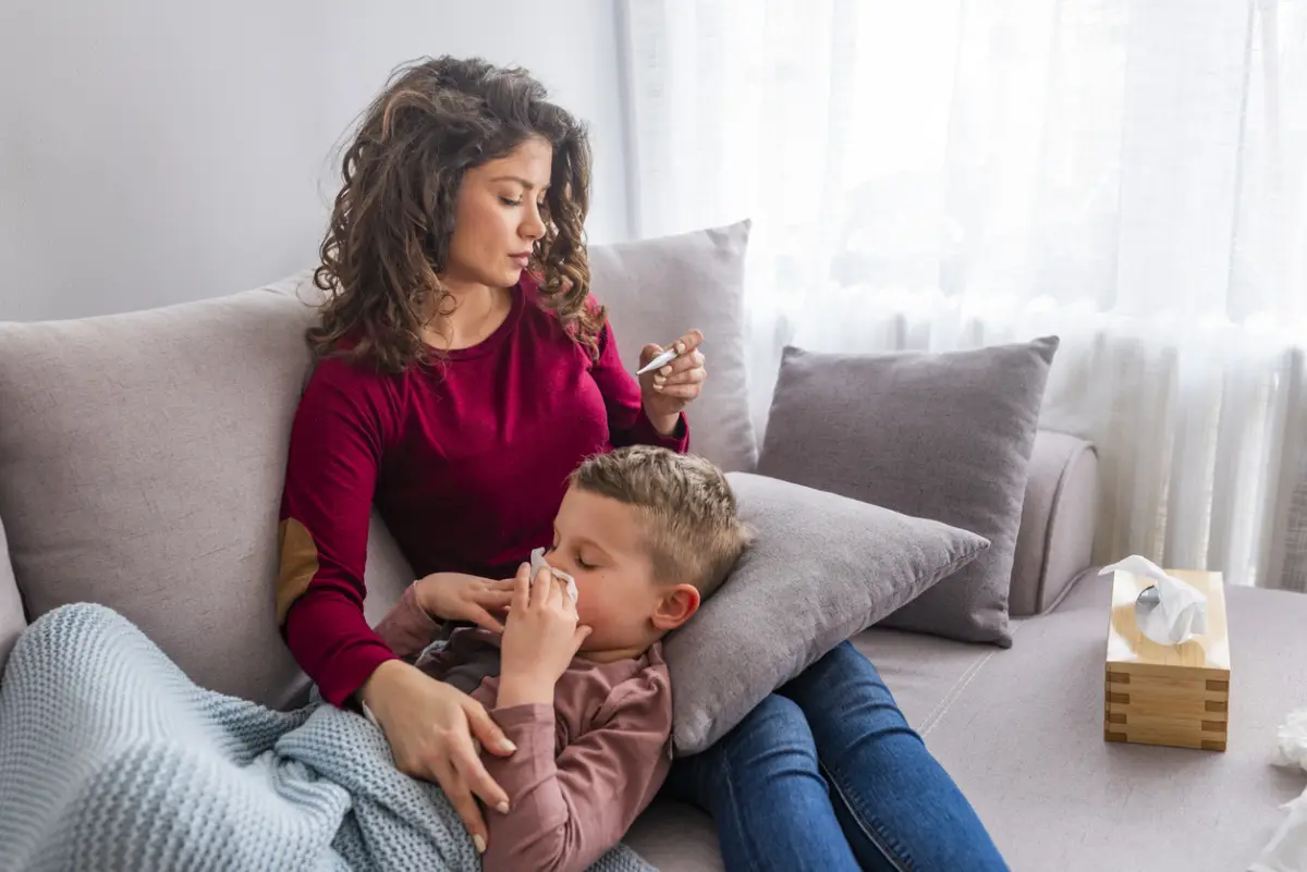 Mother checking temperature of her sick son.