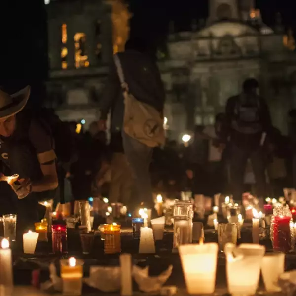 Una persona enciende una de las muchas velas en el Zócalo