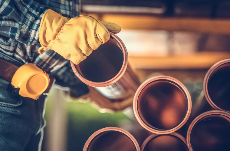 Un señor acomoda tubos de cobre.