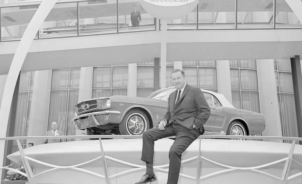 Henry Ford II sentado junto al mítico Mustang 1964 que logró catapultar a la marca en el segmento deportivo.