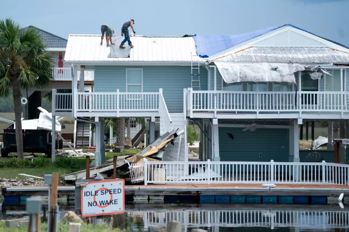 La gente trabaja en un techo después del huracán Idalia el 31 de agosto de 2023 en Keaton Beach, Florida. Idalia, que se debilitó a una tormenta tropical, tocó tierra en Keaton Beach, Florida, como un huracán de categoría 3 y causó fuertes lluvias e inundaciones repentinas.