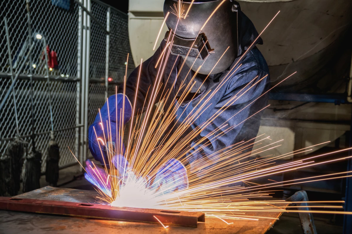 Industrial worker is welding in factory
