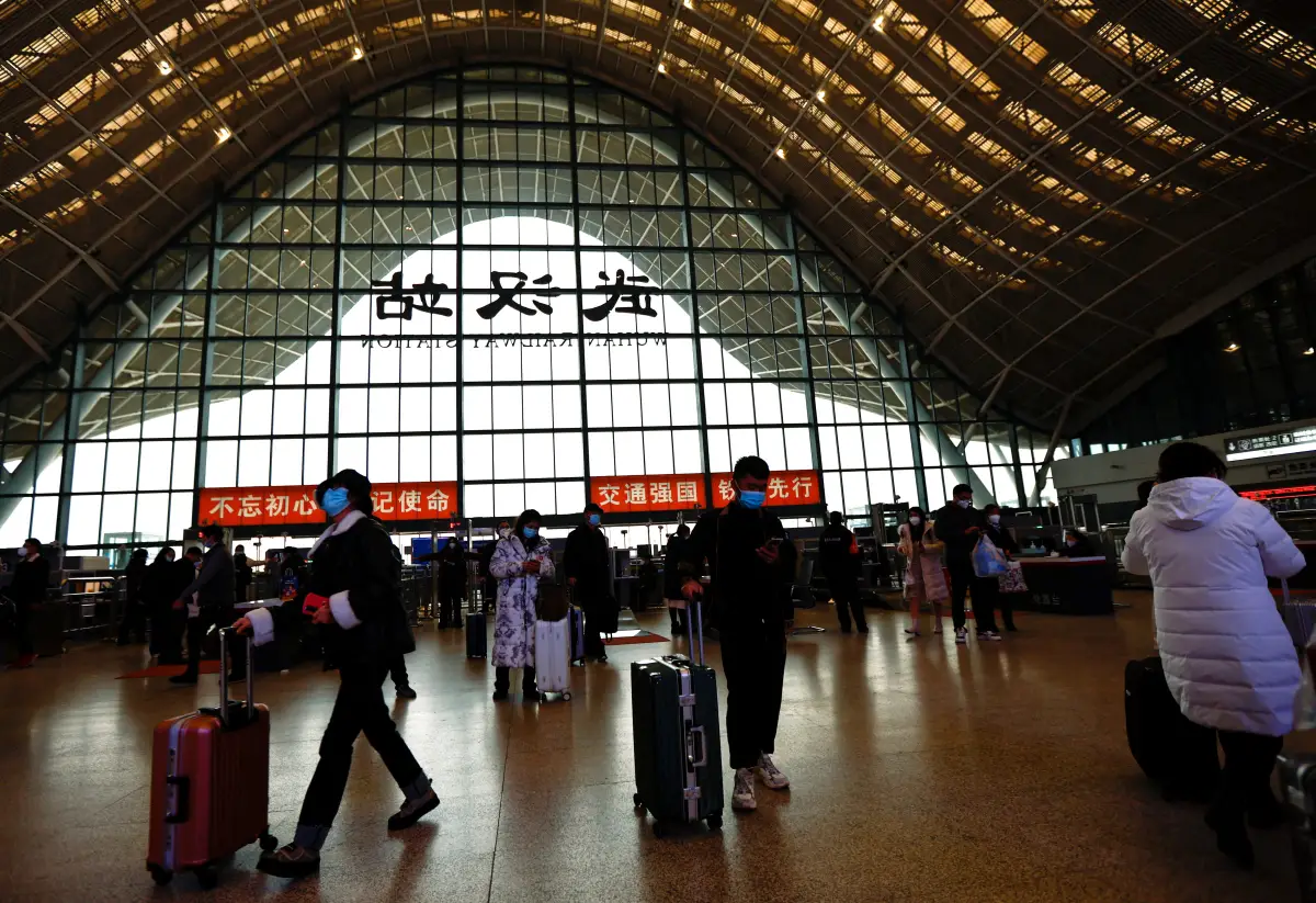 Gente espera con equipaje en una estación de tren en medio del brote de covd-19 en Wuhan, China. 