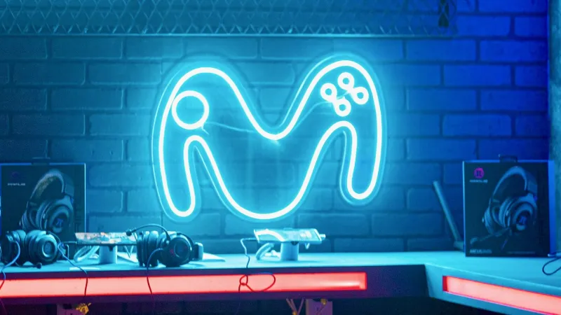 El logo de la empresa Movistar iluminada y pegada a una pared en un cuarto de jugadores de videojuegos 