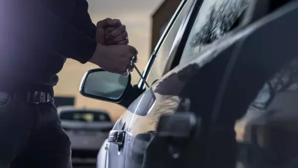 Auto thief in black balaclava trying to break into car