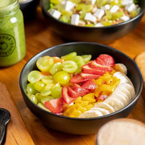 Foto de un plato de ensalada de frutas con uvas, mango, fresa y plátano.