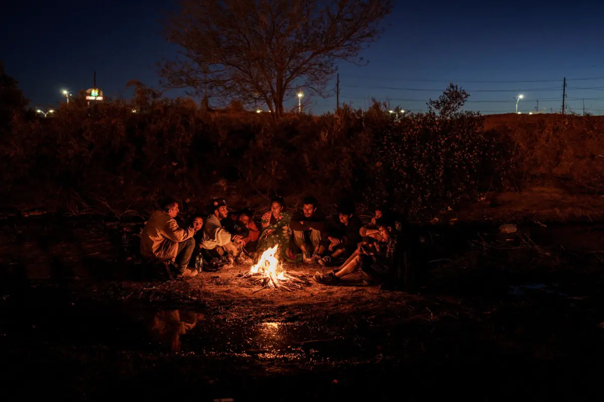 Los migrantes de Honduras se mantienen calientes alrededor de un incendio en un campamento en la frontera entre Estados Unidos y México, ya que la ley de Texas conocida como SB 4, que permite a las autoridades estatales encargadas de hacer cumplir la ley arrestar a personas sospechosas de cruzar ilegalmente la frontera entre Estados Unidos y México, continúa a través de los tribunales, en El Paso, Texas, EE. UU., el 3 de abril de 2024.