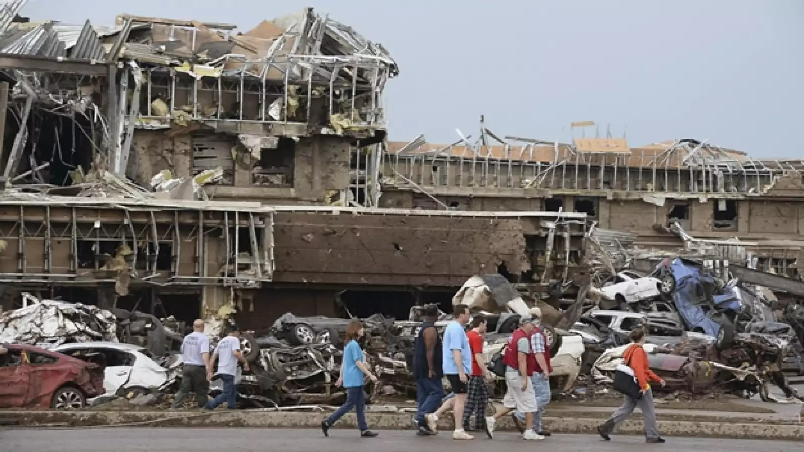 un grupo de persnoas caminan entre escombros