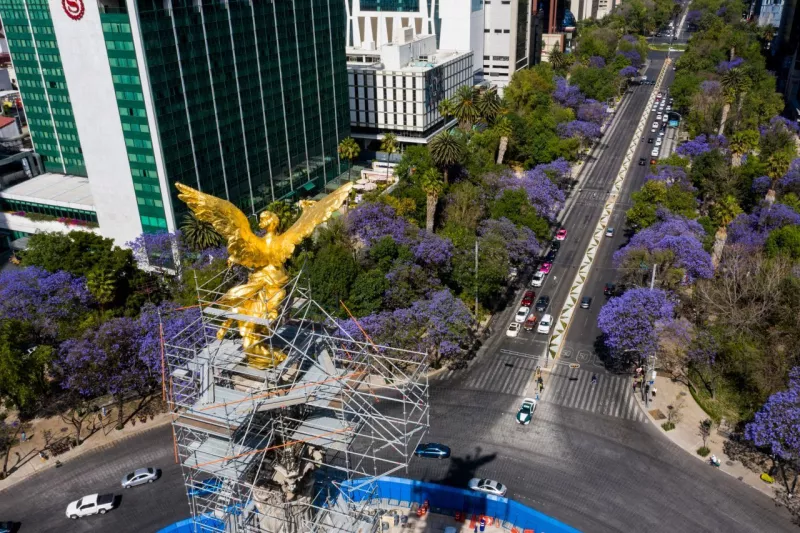 Tomas aéreas del Ángel de la Independencia donde se observa el florecer de las jacarandas durante una calurosa tarde.