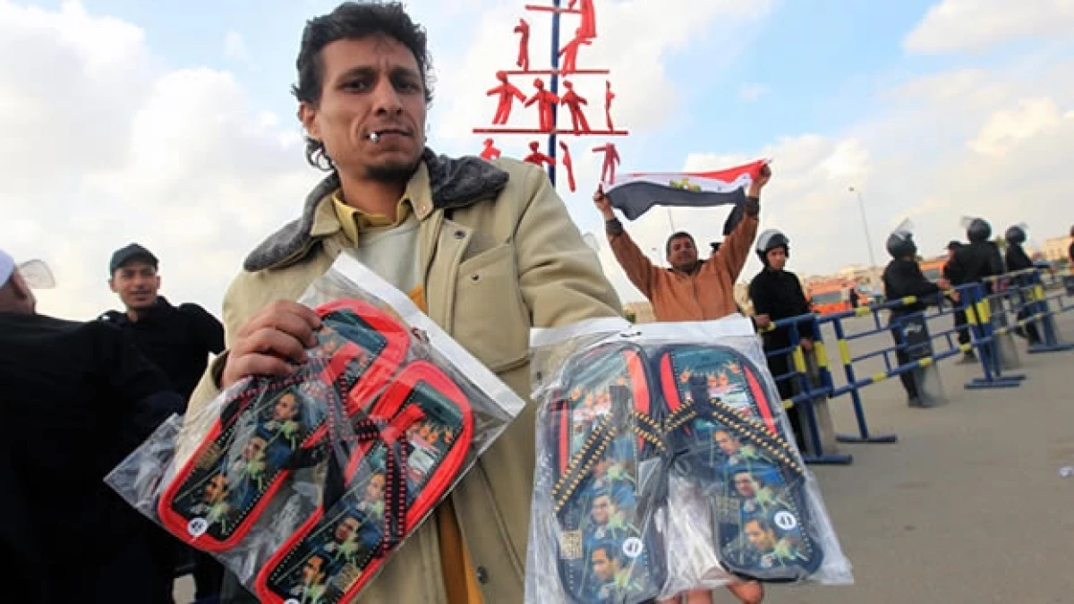 un hombre vende chanclas con la cara de mubarak