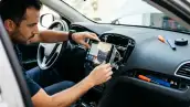 Hombre instalando una nueva pantalla en la parte frontal del carro. Estas pantallas suelen funcionar para controlar el infoentretenimiento.
