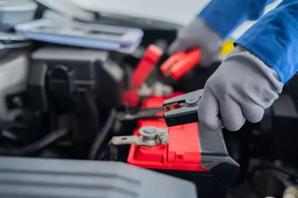 close up hand holding battery charger tools jump start vehicle battery stock photo