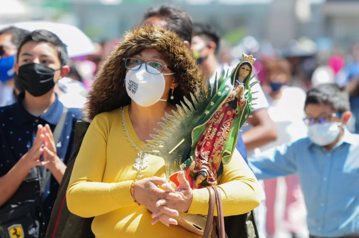 Una mujer carga su figura de la Virgen de Guadalupe.