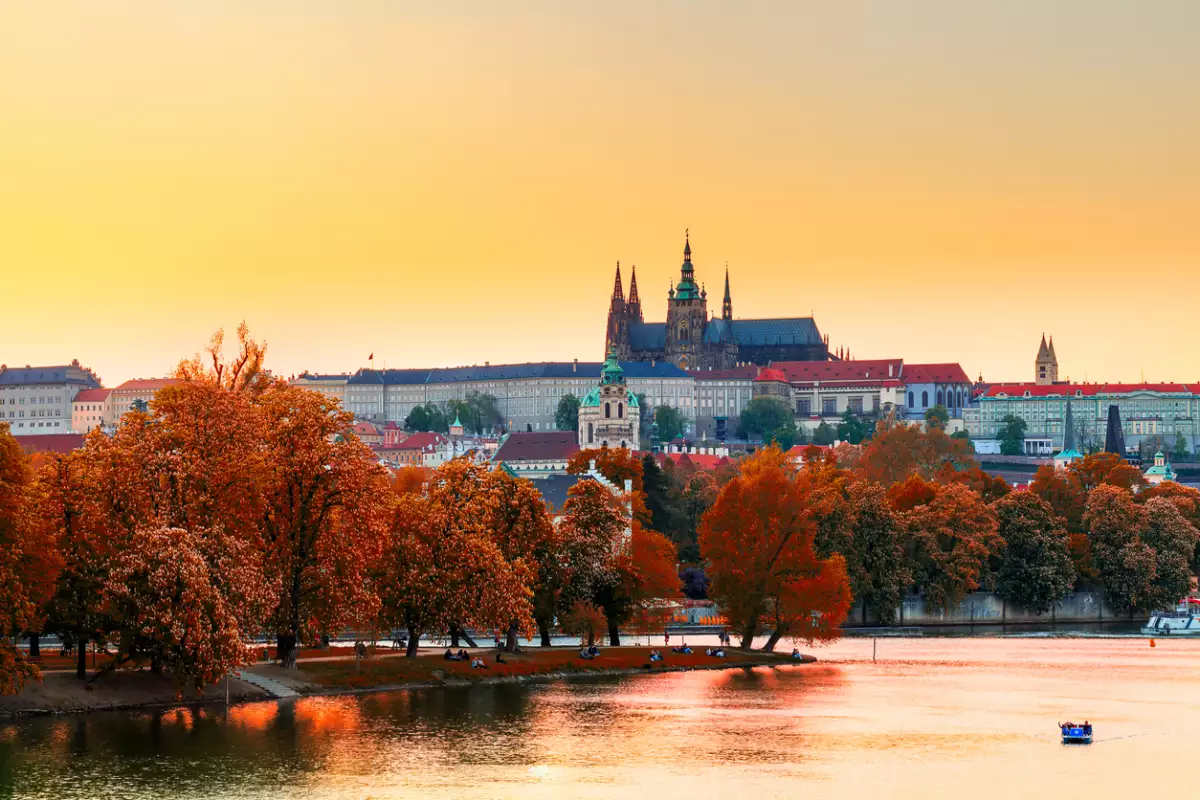 foto de praga en otoño con árboles rojos y un atardecer dorado