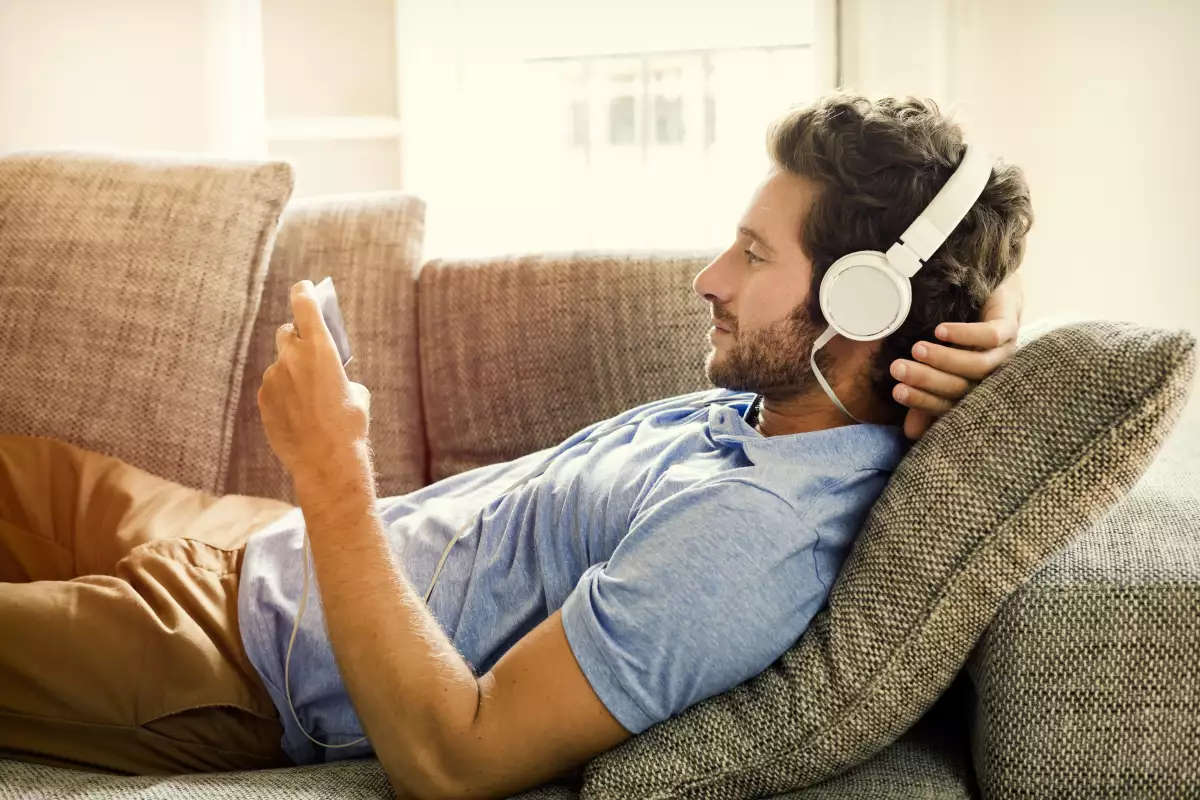 Hombre en el sofá ve una película en el teléfono móvil