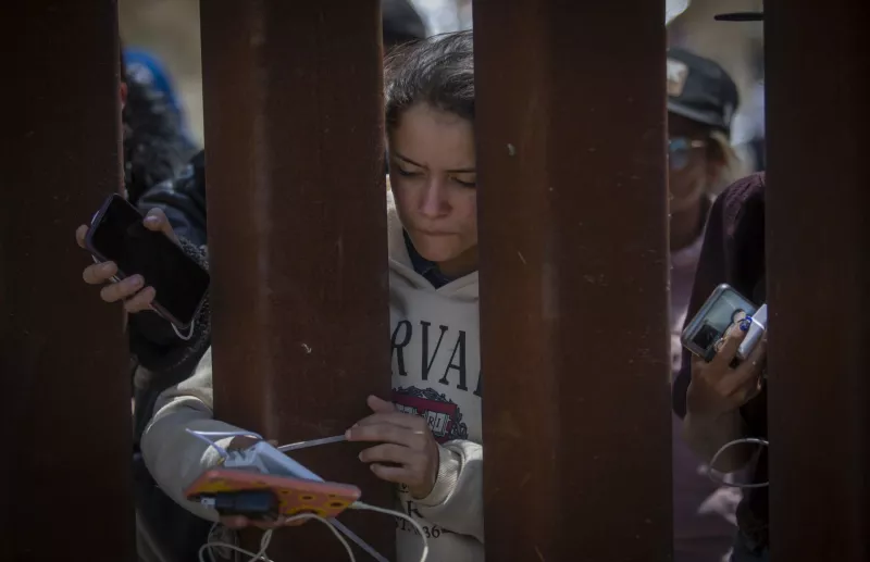 Migrantes en el muro fronterizo entre Estados Unidos y México.