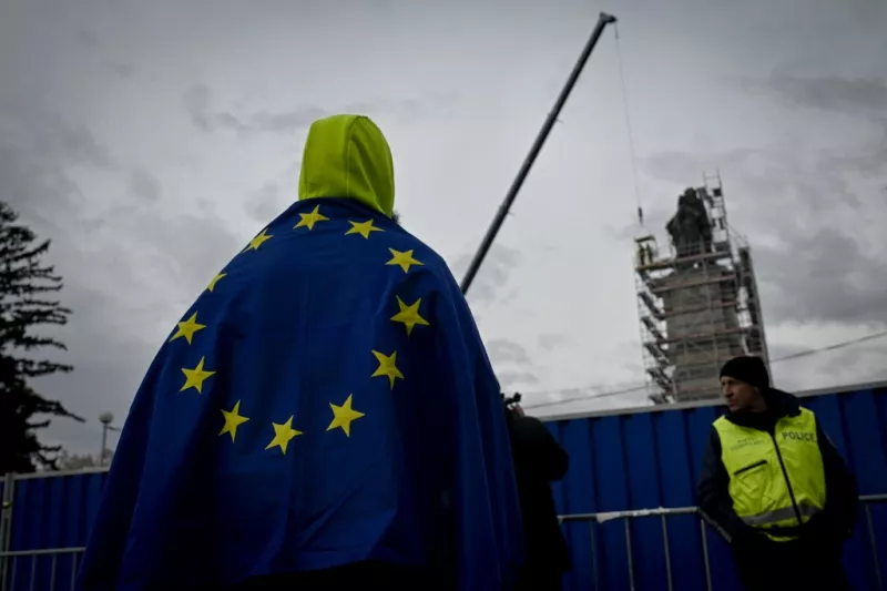 Un hombre envuelto en la bandera de la Unión Europea observa cómo los trabajadores se preparan para desmentir un monumento del ejército soviético que representa tres esculturas de bronce de un soldado soviético, un trabajador y una madre y su hijo, en Sofía, el 13 de diciembre de 2023.