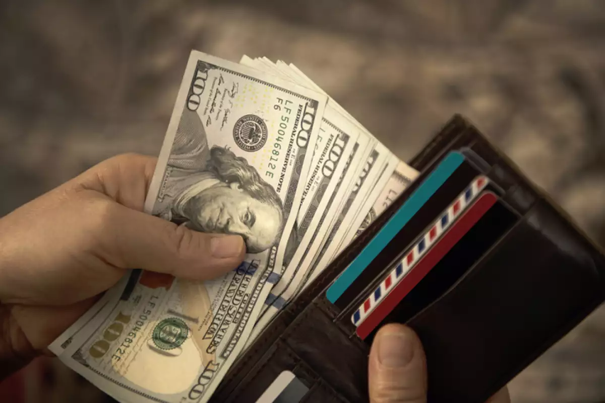High angle view of unrecognizable mature man placing USA Dollar bills into wallet