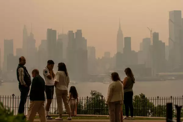 La gente está de pie en un parque mientras el horizonte de la ciudad de Nueva York está cubierto de neblina y humo de los incendios forestales de Canadá el 7 de junio de 2023 en Weehawken, Nueva Jersey.