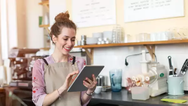 Una mujer lleva las cuentas de su negocio en un dispositivo móvil. 