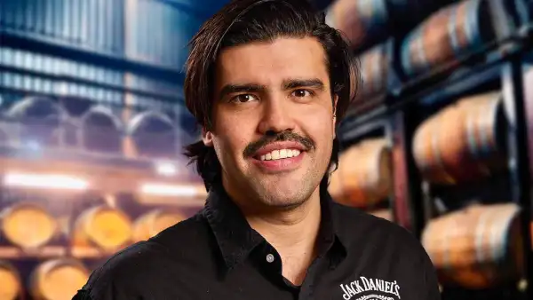 Retrato de Eduardo Toledo vestido con una camisa negra con el logotipo de la marca, frente a un fondo de barricas de whisky en una bodega.