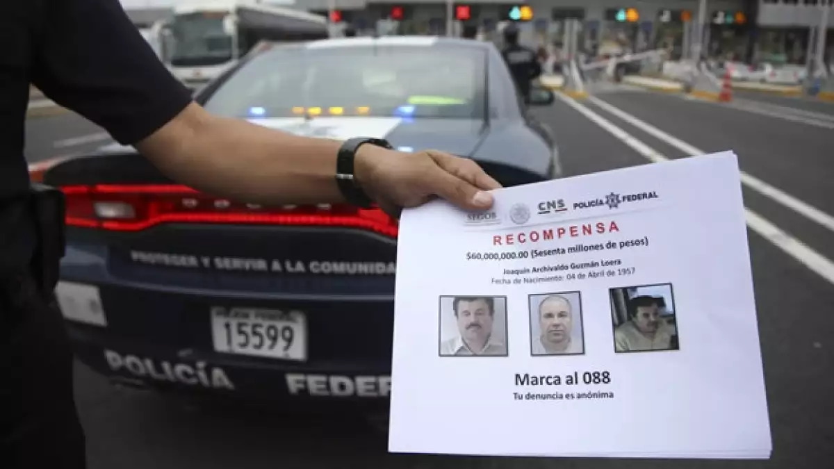 Elementos de la Policía Federal muestran folletos entregados a la ciudadanía para que puedan aportar información sobre Joaquín Guzmán