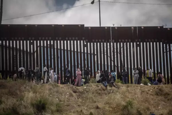 Migrantes en el muro fronterizo entre Estados Unidos y México.