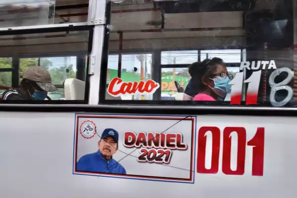 La gente viaja en un autobús público con una foto bandalizada del presidente nicaragüense Daniel Ortega el 27 de junio de 2021 en Managua, Nicaragua.
