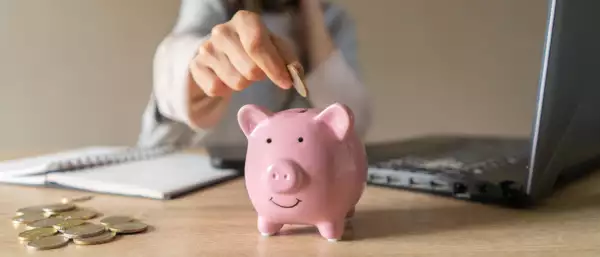 Girl makes calculations, puts funds in a piggy bank.