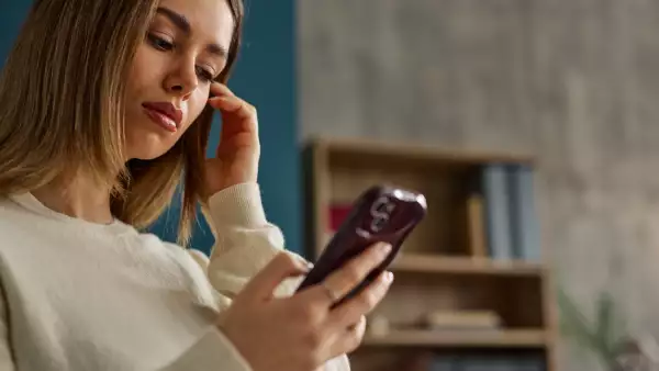 Woman checks her smartphone in a cozy home setting, conveying casual connection and modern communication