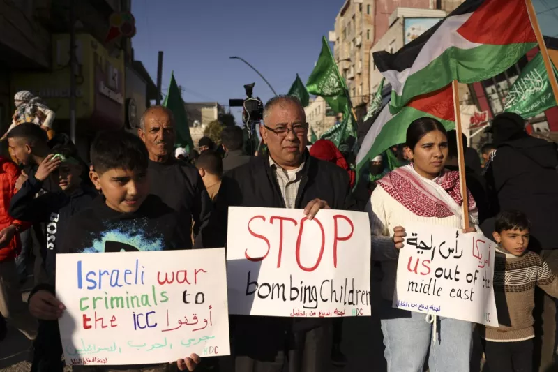 Los manifestantes palestinos sostienen carteles durante una manifestación de apoyo a la Franja de Gaza en medio de las batallas en curso entre Israel y el movimiento palestino Hamas, el 11 de diciembre de 2023, en la ciudad ocupada de Hebrón en Cisjordania.