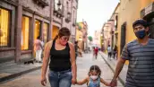 Una familia mexicana camina por la calle con cubrebocas. 